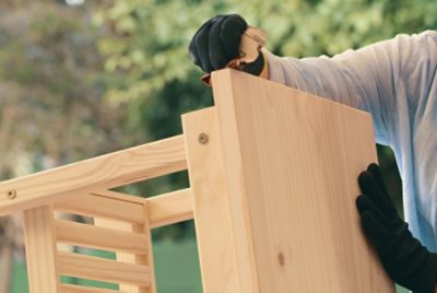 Person sanding a wood side table.