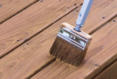 Deck stain being applied with a brush.