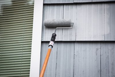 Exterior siding being rolled with paint.