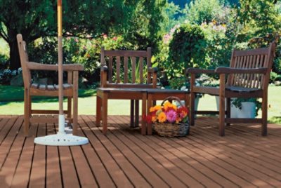 A deck with three wooden chairs and flowers.