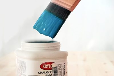 A paint brush dipped in blue Krylon paint.