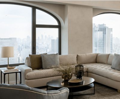 Living area with large windows, neutral couch and side tables.