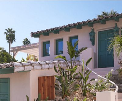 House with neutral coloring and palm trees next to it.