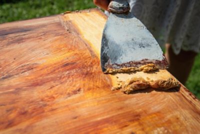 Removing stain from wood with a paint scraper.