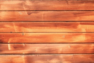 Detailed photo of a stained wooden fence, showing the rich color and texture of the wood grain.