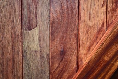 Detailed photo of a wooden fence with different stain colors applied, highlighting the uneven and mismatched appearance that can result from mixing stain types.