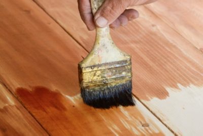 Using a brush to apply stain to wood.