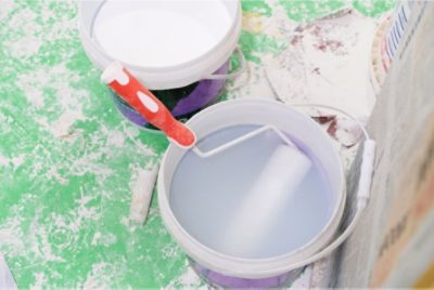A paint brush roller sitting in a one-gallon bucket of water.