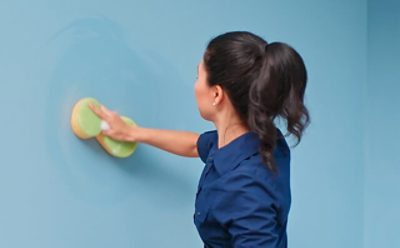 A woman pre-washing a wall surface for painting. 