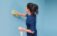A woman cleaning a wall with a sponge.