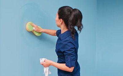 A woman cleaning a wall with a sponge.