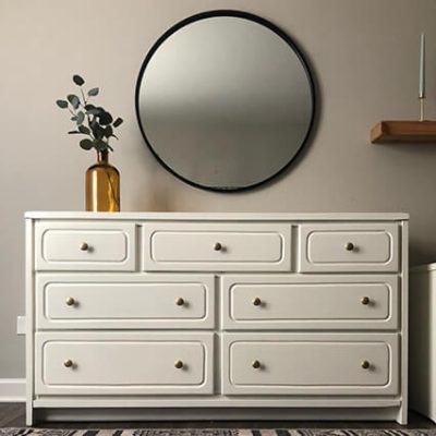 An off white dresser cabinet, neutral wall and hanging round mirror. S-W colors featured: SW 0050 Classic Light Buff.