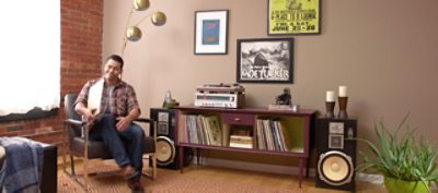 A man sitting in a leather chair listening to music from a record player.