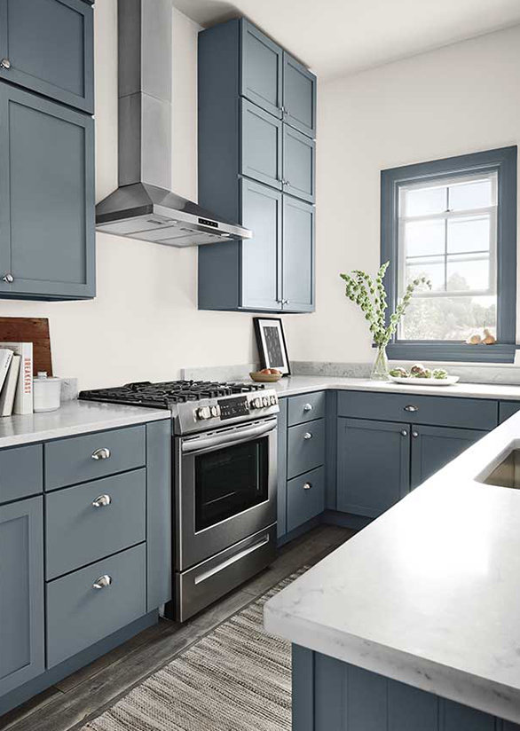 A modern kitchen with greyish blue cabinets and marble counter tops. 