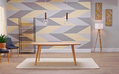 A table and area rug in front of a geometric accent wall.