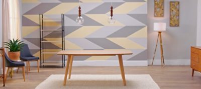 A table and area rug in front of a geometric accent wall .