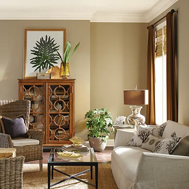 A beige living room with couch, table, bookcase, and lamp