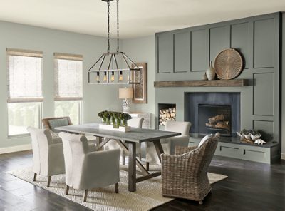 A large dining room in front of a green fireplace and windows