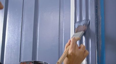 A person painting trim with a brush. SW color featured: SW 6243 Distance.