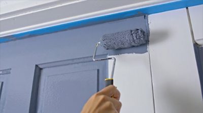 A mini roller being used to paint a door. SW color featured: SW 6243 Distance.