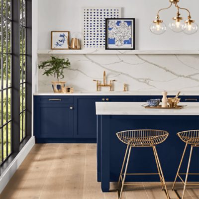 A kitchen with floor to ceiling windows, island and cabinets painted in SW 6244 Naval, and a large tile backsplash.