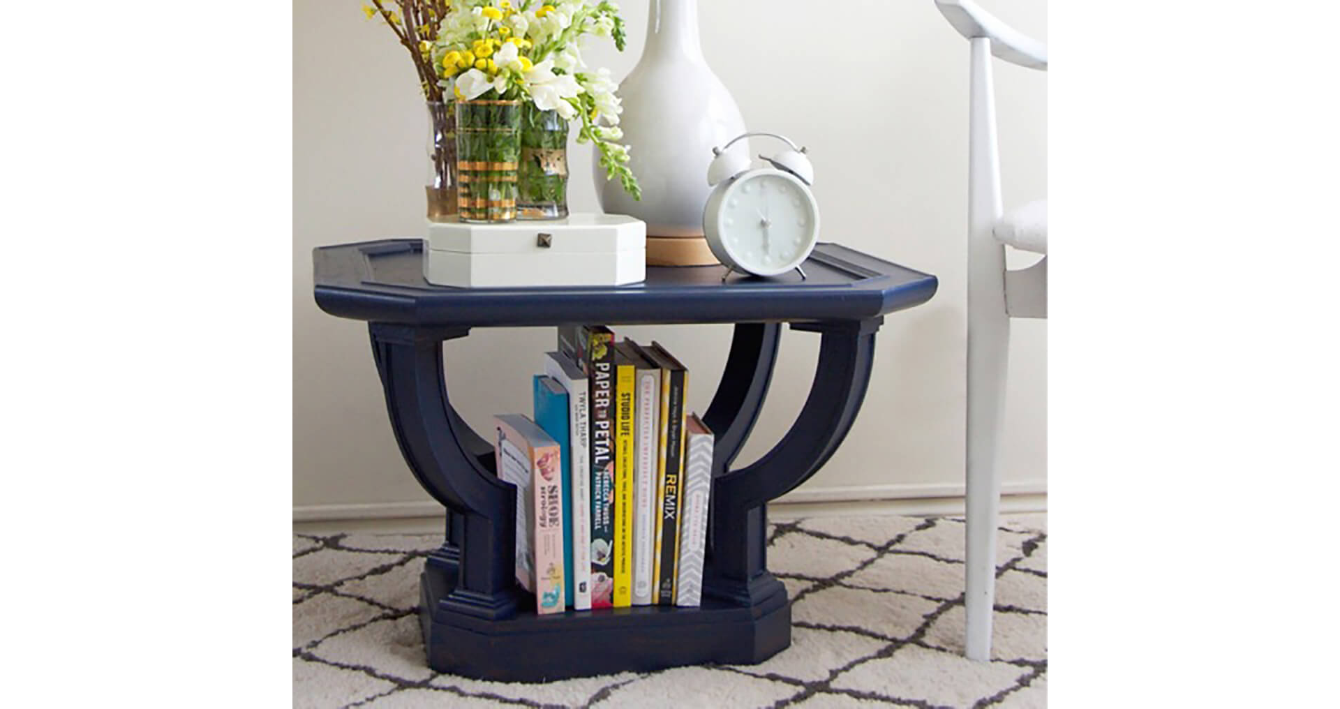 A navy blue end table with books and magazines. S-W color featured: SW 6244 Naval.