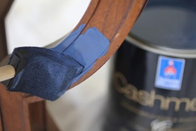 A wooden end table being painted. S-W colors featured: SW 6244 Naval.