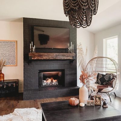 A brick fireplace painted black in a modern living room. SW colors featured: SW 6258 Tricorn.