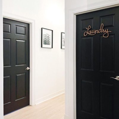 A black and white laundry room with a black painted door and sign. S-W colors featured: SW 6258.
