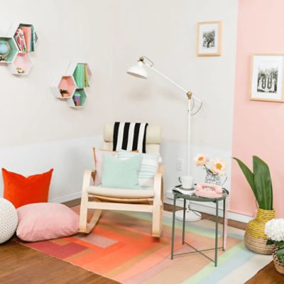 A pink and white room space with bright colored decor and white wall shelves.