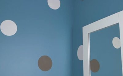 A blue wall with multi-color polka dots. 