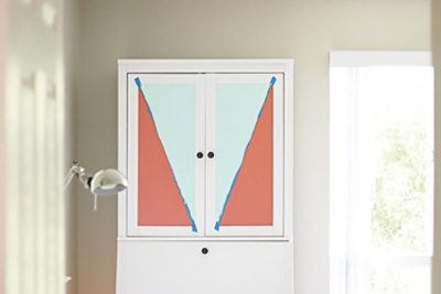 A white cabinet with coral and teal paint taped off. SW color featured: 6606 Coral Reef, SW 6757 Tame Teal.