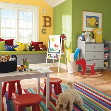 A bright kid's playroom with toys, an art stand, and dresser