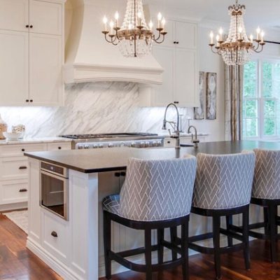 A modern toned kitchen with marble walls and white cabinetry. 