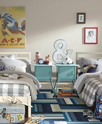 A decorated kid's bedroom with two twin beds, plaid covers, and two bedside tables made with a locker door