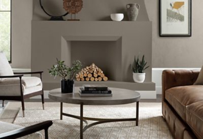 A formal living room with gray fireplace and walls, chairs, couch and round table