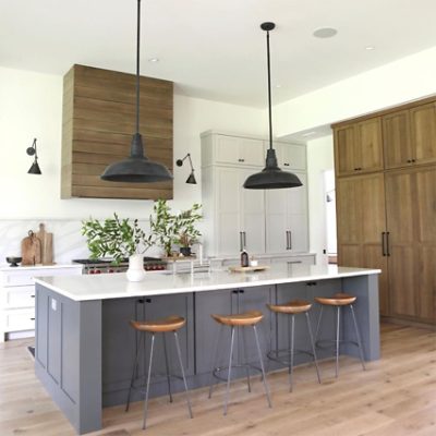 A modern-designed kitchen with a slate gray island and wooden bar stools. 