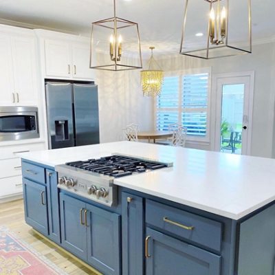 A modern kitchen with a blue kitchen island and white counter tops. 