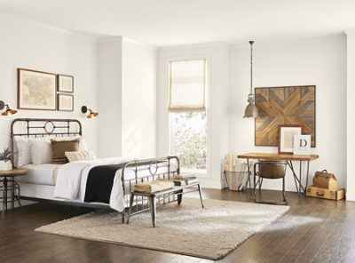 A white living room with leather couch, large neutral rug and yellow closet doors