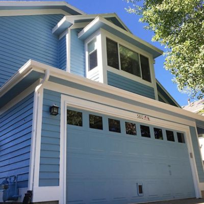 A light blue painted exterior home with an attached garage door. S-W color featured: SW 7608.