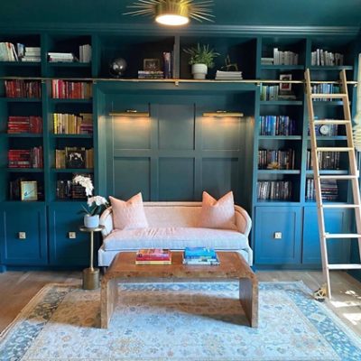A dark teal reading nook with dark teal shelves and a sofa. SW color featured: SW 7623 Cascades.