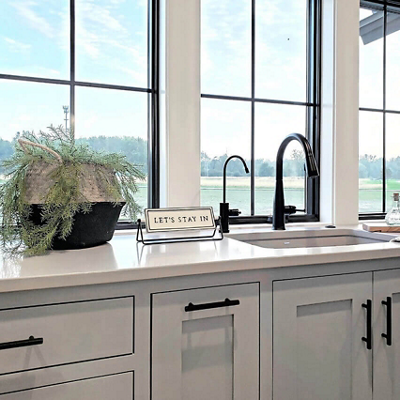 A kitchen sink with light grey painted cabinets. S-W featured color: SW 7660 Earl Grey