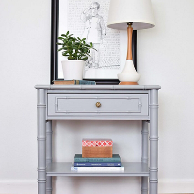 A gray end table with a lamp and decorations. S-W color featured: SW 7662 Evening Shadow.