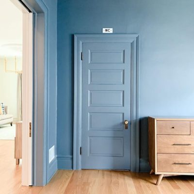 A blue bedroom and closet door with hardwood floors. S-W featured color: 7665 Wall Street.