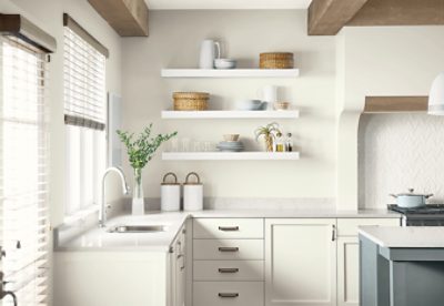 A modern kitchen with open shelves, island and soft white walls and cabinets