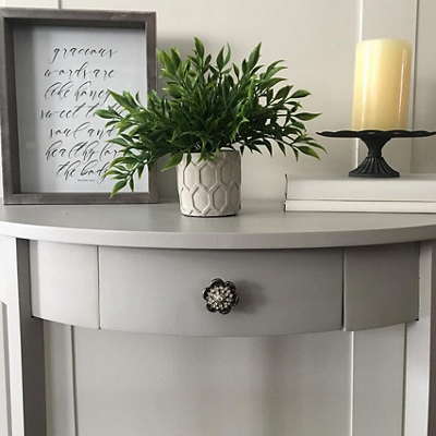A gray end table with a candle and plant. S-W color featured: SW 7672 Knitting Needles.
