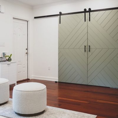 A white living room with green barndoors. S-W color featured: 9130 Evergreen Fog.