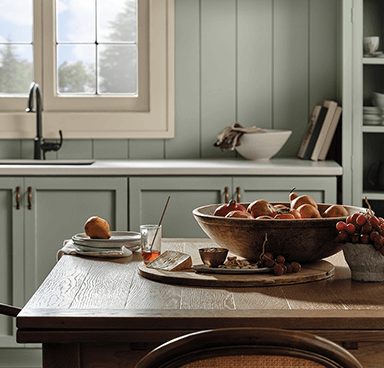 A kitchen with green walls and cabinets and table