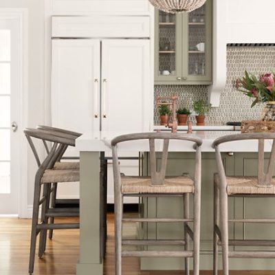 A modern kitchen with wooden bar stools and green undertone paints. 