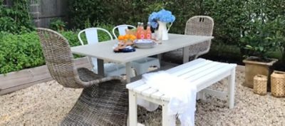 An outdoor wool dining table with wicker chairs and a white bench. SW colors featured: SW 9171.